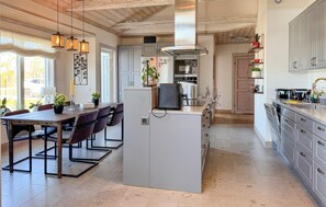 A modern kitchen with a central island, built-in appliances, and a dining area with a table and chairs. - Amazing home in Visby (Visby)