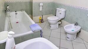 Een badkamer met een bad, toilet, bidet en wastafel.