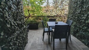 Een terras met een tafel en stoelen, omringd door een metalen hek en beplanting.