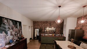 Een moderne keuken met een bakstenen muur, een eetgedeelte met een marmeren tafel en een groot stadsgezicht op de muur.