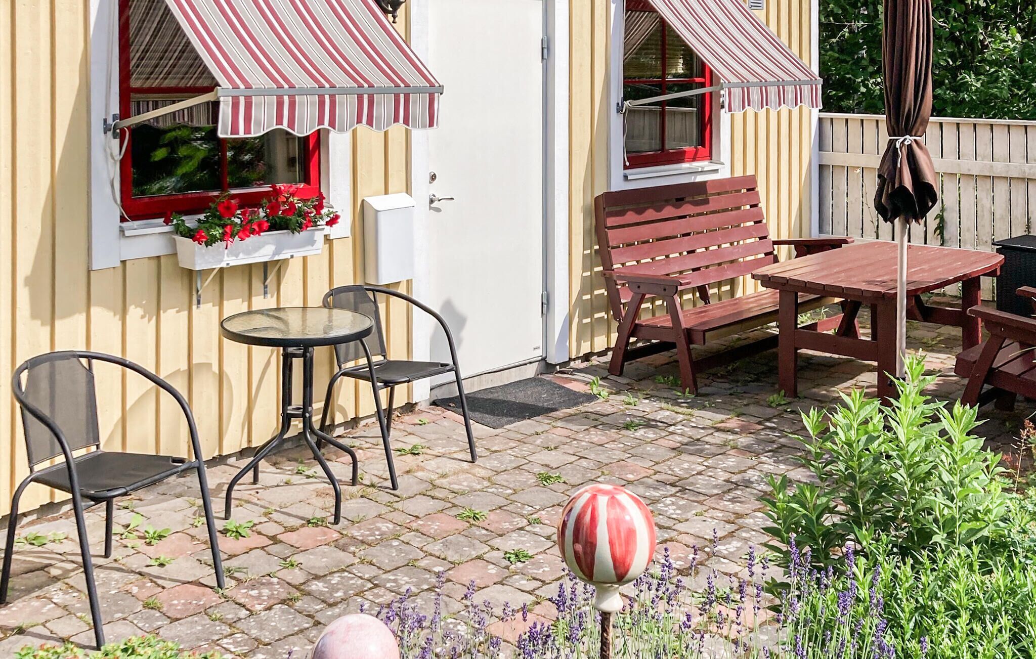 Eine Terrasse mit Tisch, Stühlen, einer Bank und einem Sonnenschirm.