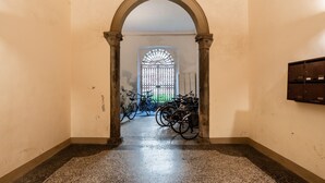 A hallway with an arched doorway leading to a room with bicycles. - Sogno Apartment Lucca – Bright Loft in Historic Center, Sleeps 4 (Lucca)
