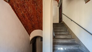 A staircase with a metal handrail, leading to a room with a brick ceiling and white walls. - Sogno Apartment Lucca – Bright Loft in Historic Center, Sleeps 4 (Lucca)