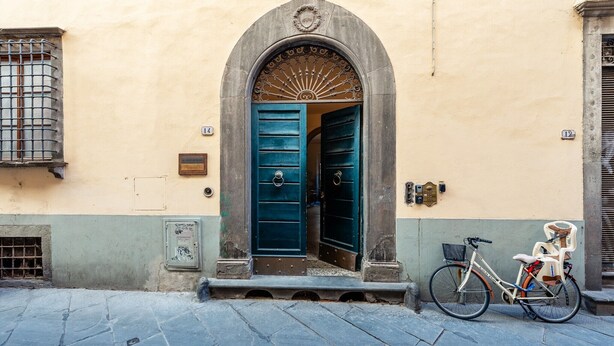 A building with a blue door, a bicycle, and a mailbox. - Sogno Apartment Lucca – Bright Loft in Historic Center, Sleeps 4 (Lucca)