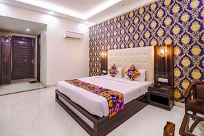 Camera d'hotel con un letto, un comodino, una sedia, un condizionatore d'aria a muro e carta da parati decorata.