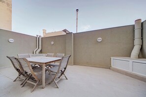 An outdoor patio with a wooden table and chairs, a white wall, and a chimney. - Pembroke 2BR Near Sea home |5 min Walk to Beach (Pembroke)