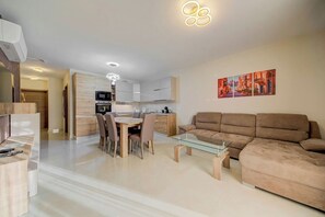 Ein modernes Wohnzimmer mit einer Couch, einem Glastisch und einem Essbereich mit Stühlen und einem Tisch.