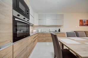 Eine moderne Küche mit Einbaugeräten, einem Essbereich mit Tisch und Stühlen sowie einem Gemälde an der Wand.