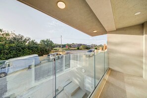 Ein modernes Gebäude mit einem Glasbalkon mit Blick auf eine Straße, auf der Autos geparkt sind und ein Stoppschild steht.