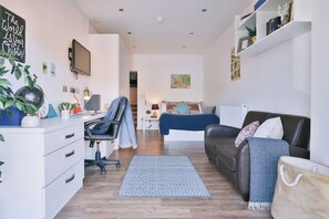 A modern living room with a desk, a sofa, a coffee table, and a bookshelf. - Student Only 136 New Walk (Leicester)