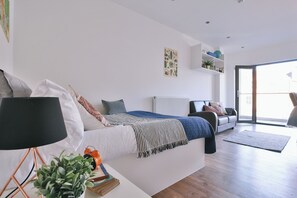 A modern bedroom with a bed, bedside table, lamp, and a potted plant. - Student Only 136 New Walk (Leicester)