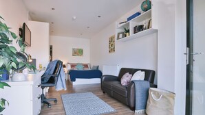 Una sala de estar moderna con un sofá, un escritorio, una silla, una alfombra y una planta en maceta.