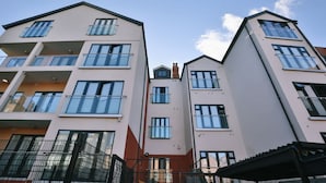 Un edificio residencial de varios pisos con balcones, ventanas amplias y cielo despejado.