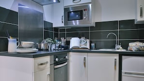 Una cocina moderna con electrodomésticos de acero inoxidable, armarios blancos y un salpicadero negro.