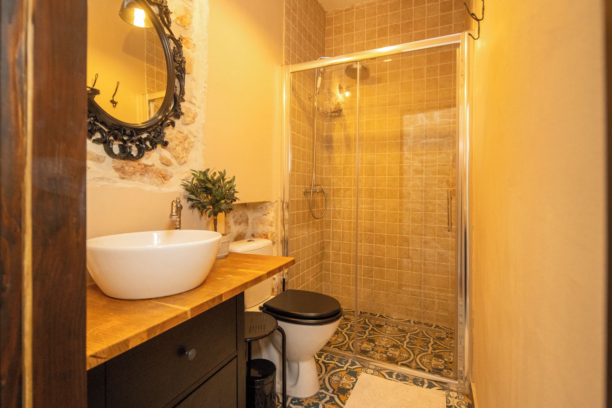 A bathroom with a white sink, black toilet, and a glass shower enclosure.