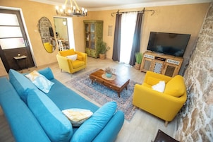 A living room with a sofa, armchairs, a coffee table, a television, and a stone wall.