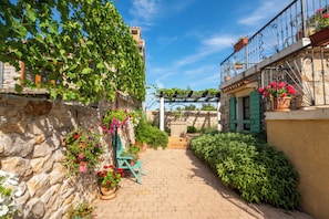 A narrow alleyway with stone walls, potted plants, and a wooden bench. - Villa Božini dvori Biograd (Sveti Filip i Jakov)