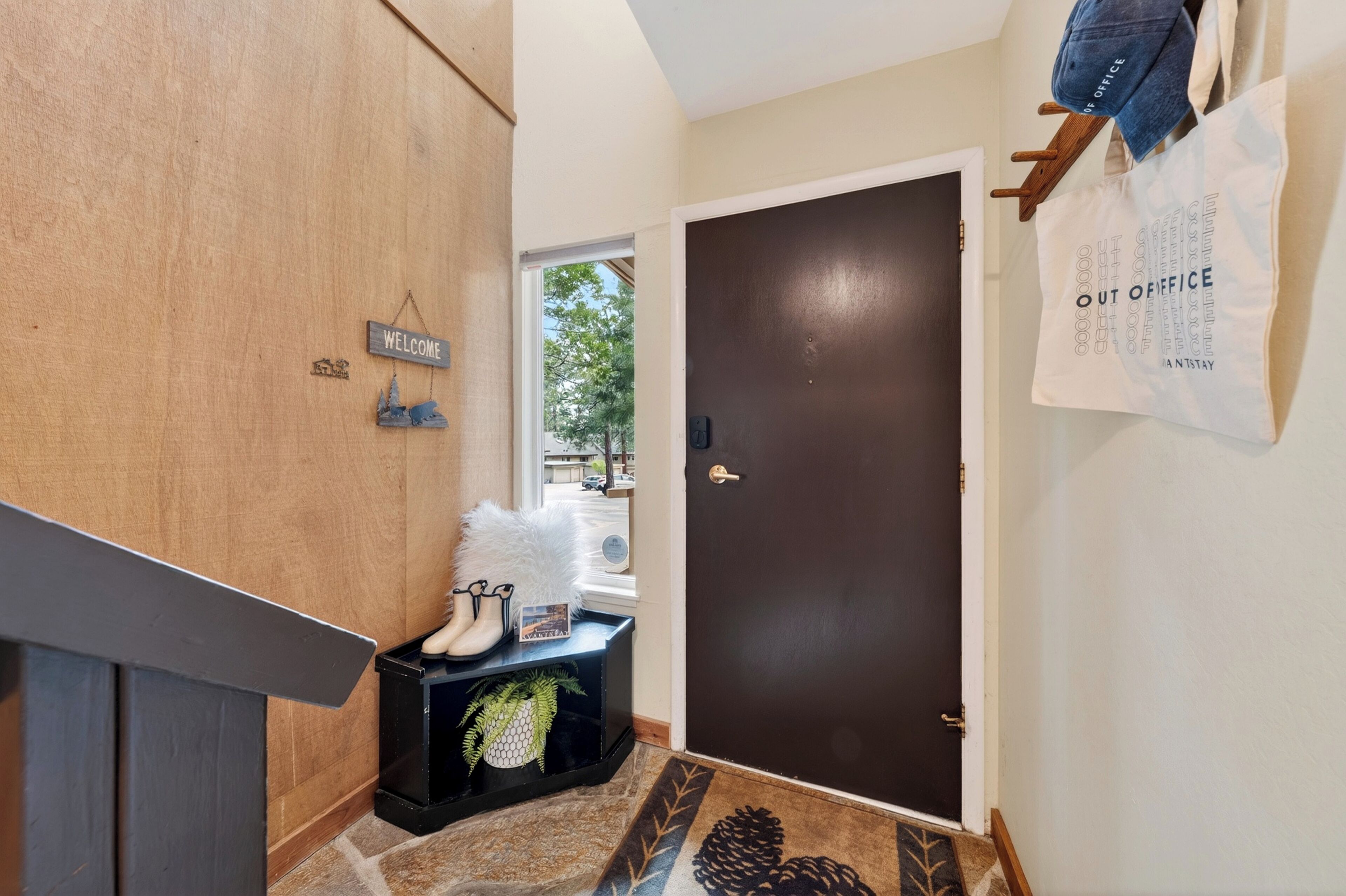 Un couloir avec un mur en bois, une pancarte de bienvenue, une porte et un sac accroché au mur.