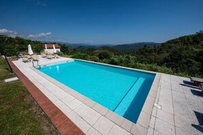 Ein rechteckiger Swimmingpool mit klarem, blauem Wasser, umgeben von einer Fliesenveranda.