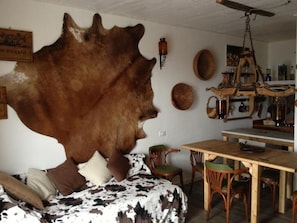 Ein Zimmer mit einem großen Fellteppich, Holzmöbeln und einem Deckenventilator.