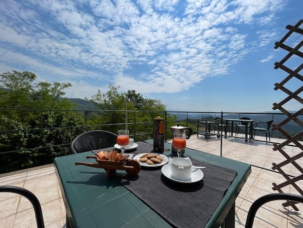 Ein Tisch ist mit Frühstücksleckereien gedeckt, mit Blick auf die Landschaft und einem wolkenlosen Himmel.