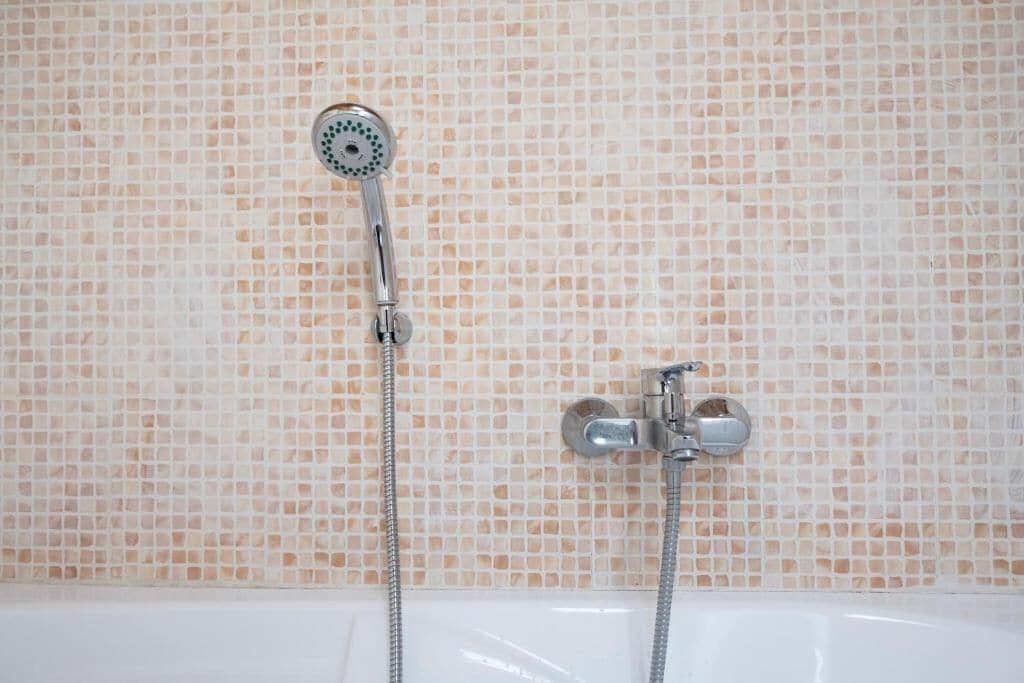 A bathroom with a shower, a bathtub, and a tiled wall.