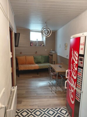 Un espacio habitable compacto con sofá, mesa de comedor, sillas, refrigerador y una ventana.