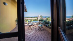 Un balcon avec une table et des chaises, une vue sur la mer et un mur jaune.