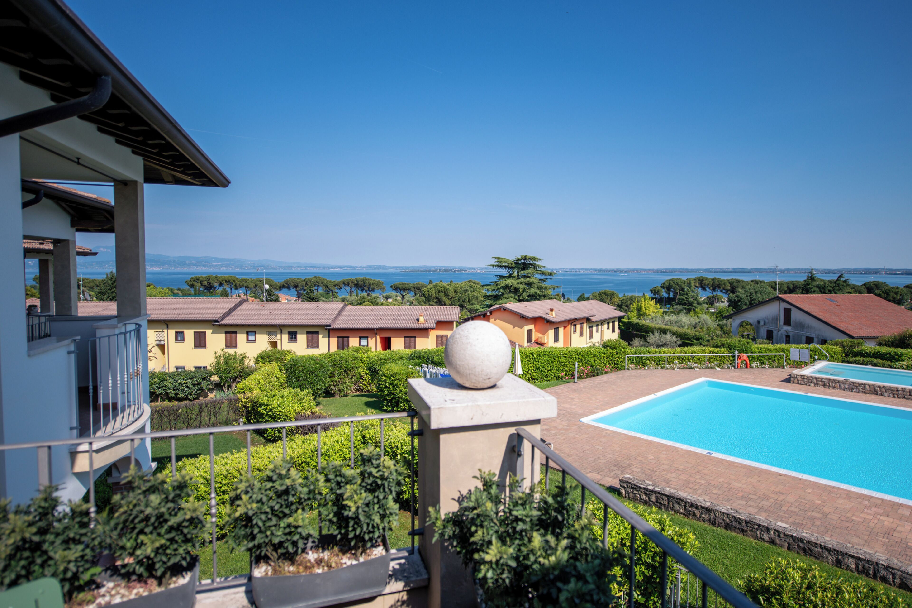 Zona residencial con piscina, una gran esfera decorativa y vista al mar.