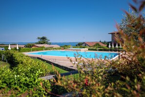 Una piscina rodeada de vegetación, con vistas claras al mar de fondo.