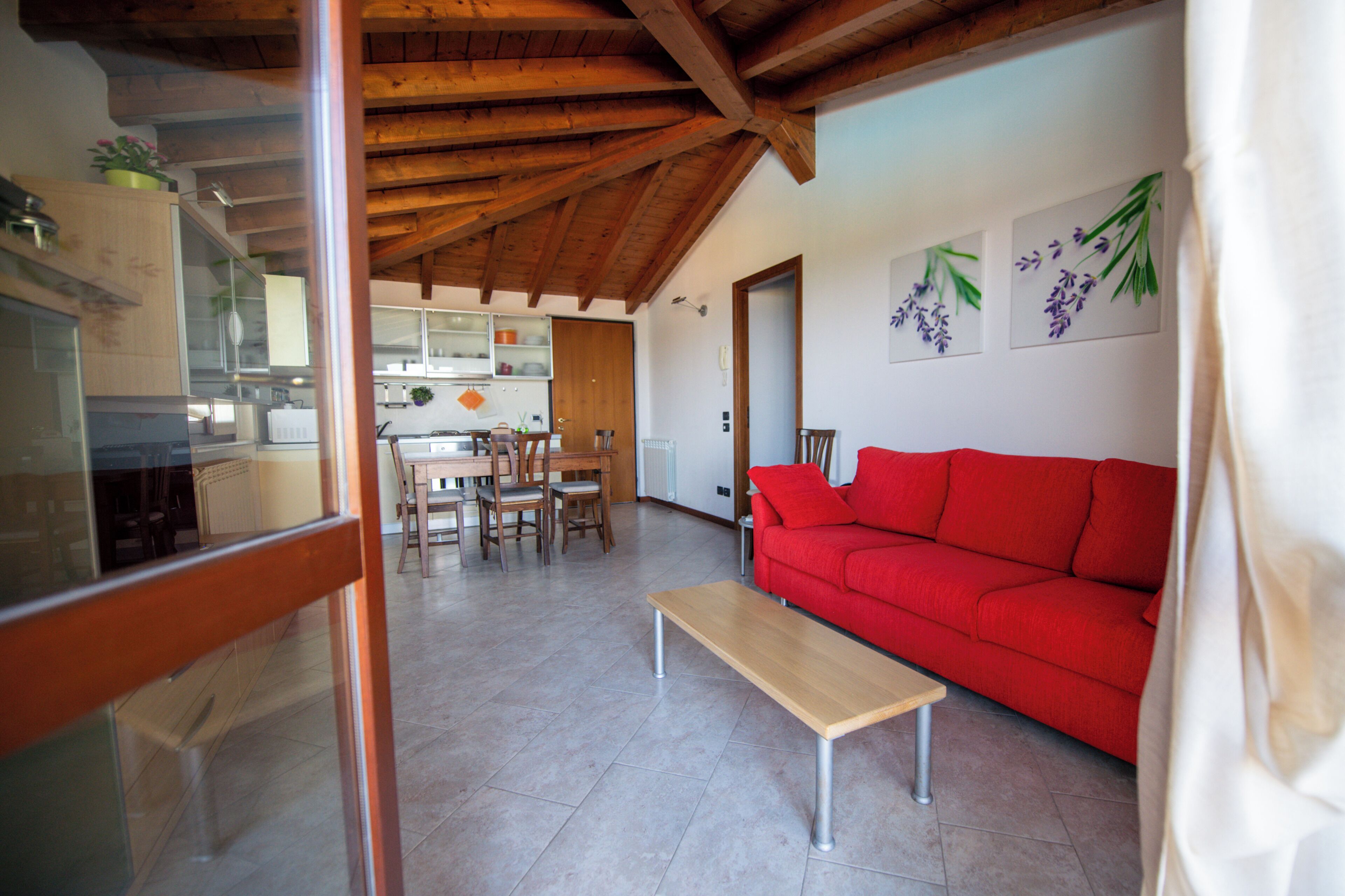 A living room with a red sofa, wooden dining table, and chairs.