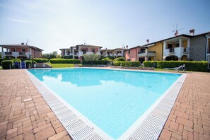 Una piscina rodeada de senderos de ladrillo y edificios residenciales con balcones.