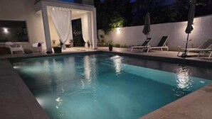 Ein Schwimmbecken mit einer weißen Struktur und Liegestühlen.