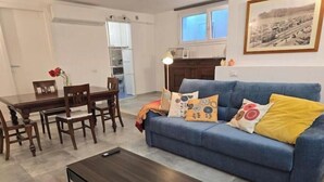 Ein Wohnzimmer mit einem blauen Sofa, einem Couchtisch und einem Essbereich mit einem Holztisch und Stühlen.