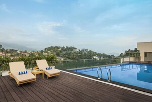A rooftop pool with lounge chairs and a view of a cityscape.