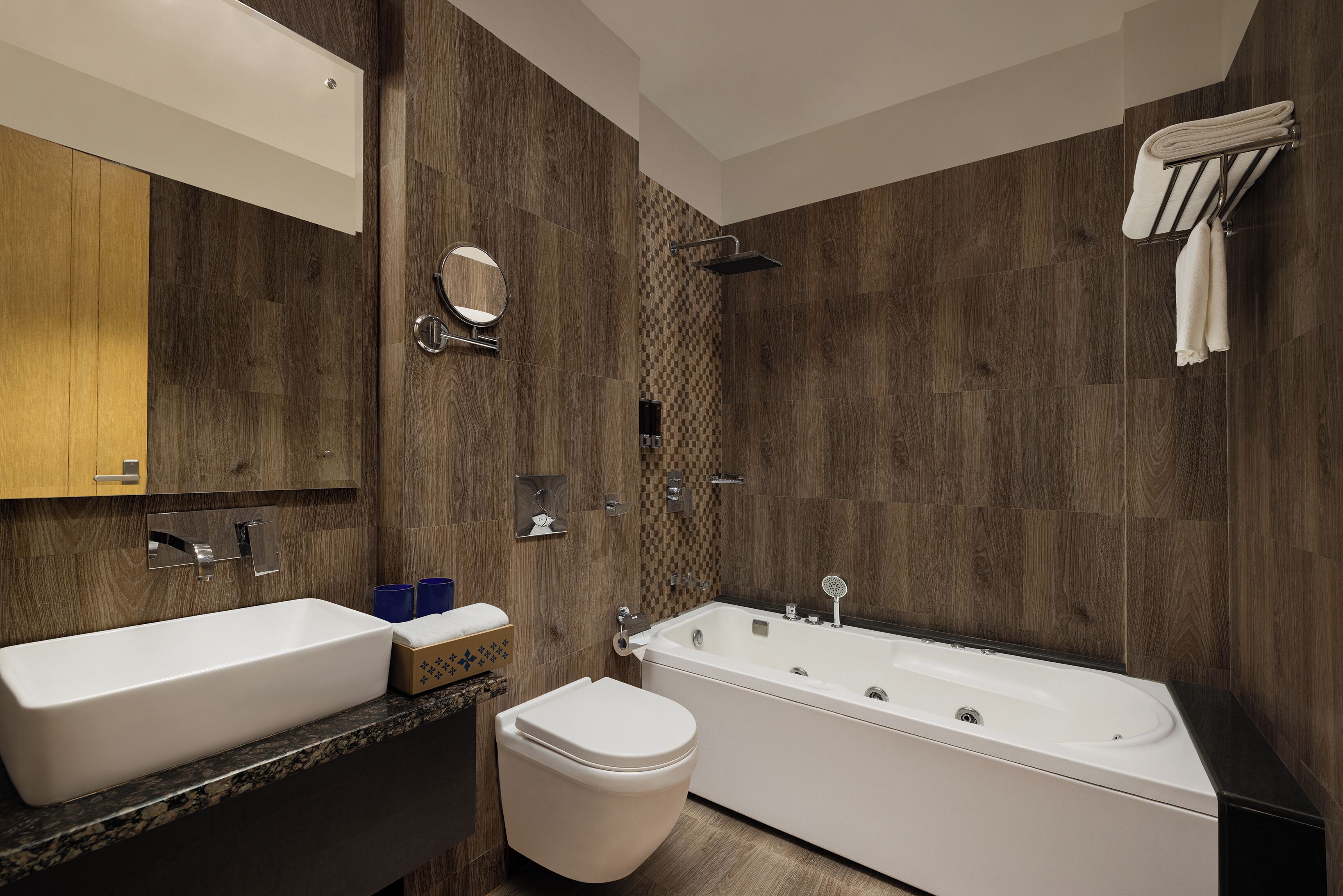 Une salle de bain moderne dotée d’une grande baignoire, de toilettes séparées, d’un meuble-lavabo avec miroir et d’un espace douche.