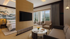 Ein Hotelzimmer mit einem Bett, einem Flachbildfernseher, einem Sofa, einem Couchtisch und einem Balkon mit Blick.