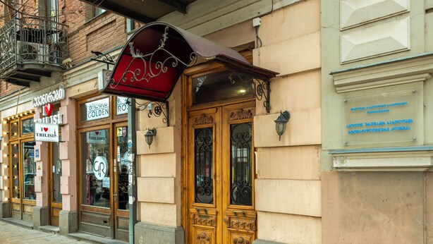 A building with ornate wooden doors, a red awning, and a sign that reads 'I ♥ BRITISH.' - HB apartments Marjani (Tbilisi)