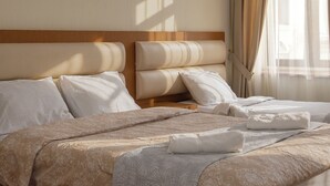 A neatly made bed with a patterned bedspread, pillows, and a folded towel. - HB apartments Marjani (Tbilisi)