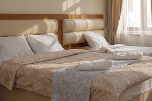 A neatly made bed with a patterned bedspread, pillows, and a folded towel. - HB apartments Marjani (Tbilisi)