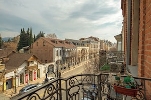 A street view with buildings, a balcony with a railing, and a parked car. - HB apartments Marjani (Tbilisi)