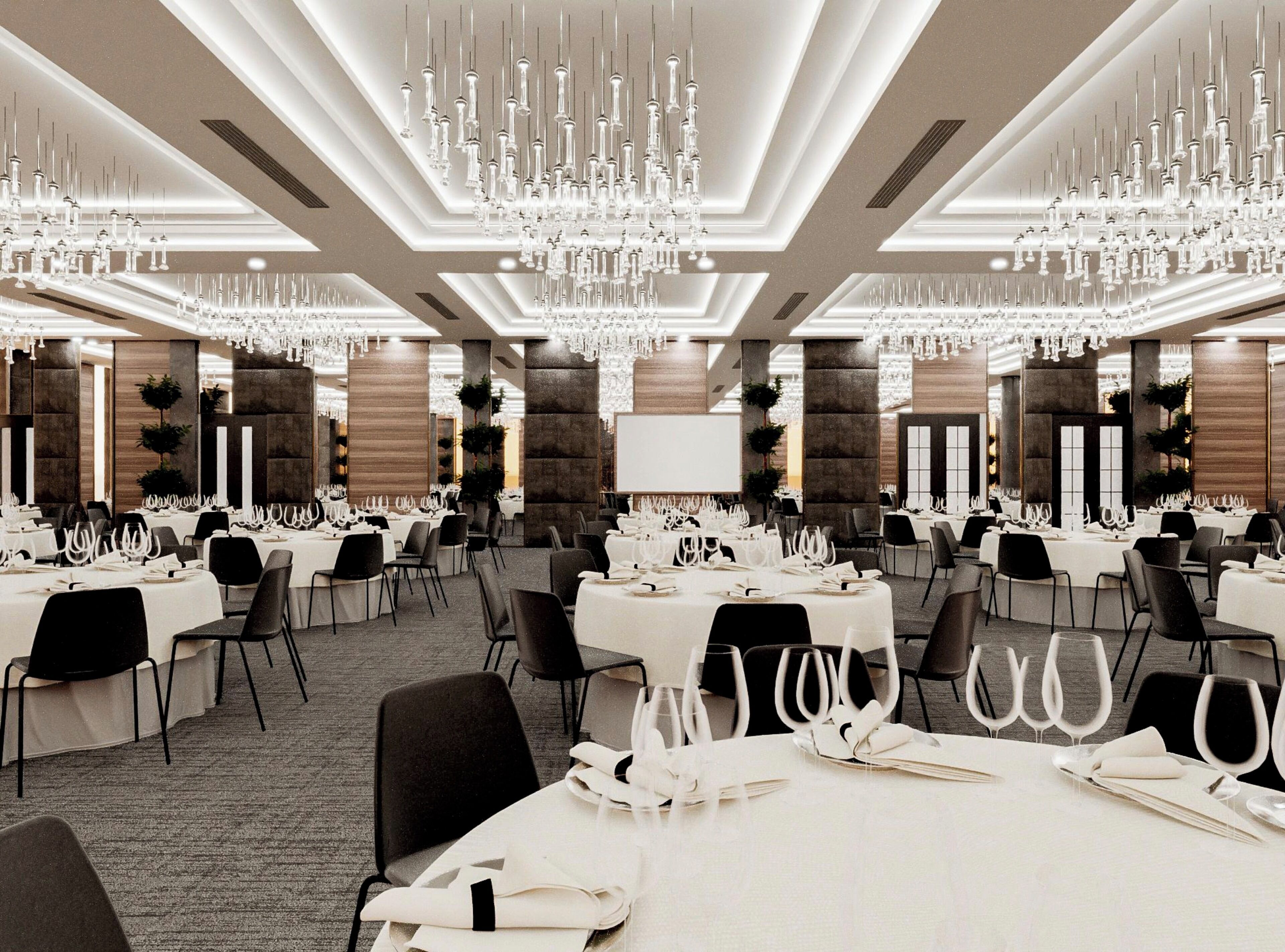 A banquet hall with multiple tables set for dining, featuring chandeliers and modern decor.
