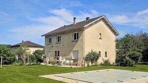 A two-story house with a large lawn and a paved area in front. - Charming house with swimming pool in the heart of Périgord Noir (LE BUGUE 24260) (Le Bugue)