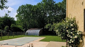 A backyard with a tennis court, a covered structure, and a wall with climbing roses. - Charming house with swimming pool in the heart of Périgord Noir (LE BUGUE 24260) (Le Bugue)