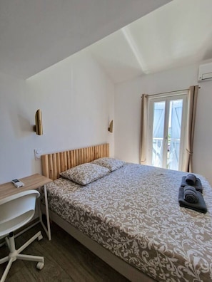 Ein Schlafzimmer mit einem Bett, einem Schreibtisch, einem Stuhl und einem Fenster mit Vorhängen.