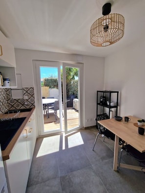 Eine moderne Küche mit Essbereich, einer Schiebetür zu einer Terrasse und einer Deckenleuchte.