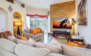 Ein Wohnzimmer mit einer Couch, Sesseln, einem Fernseher und einer Holzwand.