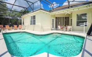 Une piscine dotée d’un patio couvert, d’un ventilateur de plafond et de meubles d’extérieur.