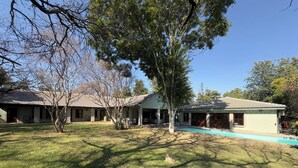 A residential property with a swimming pool, multiple buildings, and a well-maintained lawn. - Room-heron Room - Staynest Guesthouse (Johannesburg)