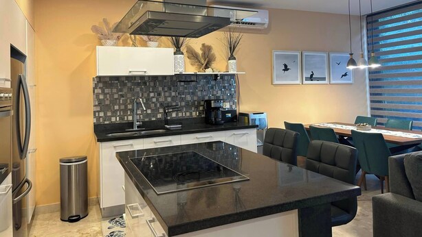 A modern kitchen with a central island, a built-in stove, and a stainless steel range hood. - Amazing Akumal Townhouse With Private Plunge Pool (Akumal)